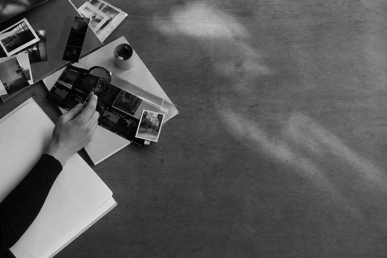 Mesa de arquivo com fotografias e materiais em processo de seleção